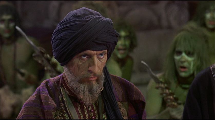 Tom Baker as Koura, surrounded by green tribesmen